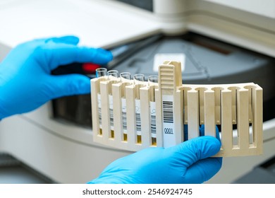 Laboratory technician handling test tubes in a lab. A technician in blue gloves is carefully managing test tubes while working in a laboratory setting, focused on analysis. - Powered by Shutterstock