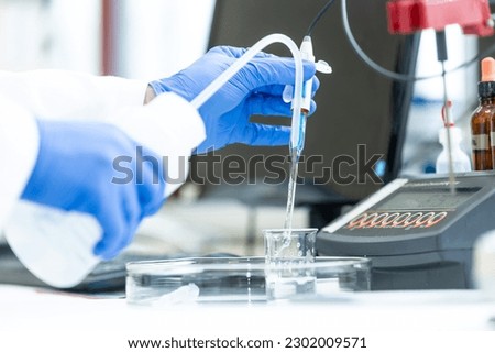 Laboratory technician holding glass electrode for measuring of pH of the solution using pH meter., analytical or electro chemistry laboratory, lab concept