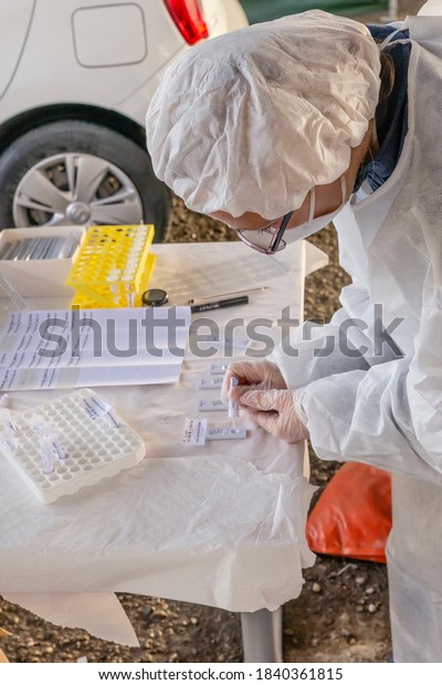 A laboratory\
technician performs a rapid covid-19 test with a device that gives\
the result immediately, in a drive through located in a city\
street, Empoli, Florence,\
Italy