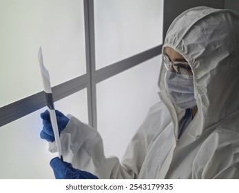 Laboratory technician in protective gear examining a sample in a sterile environment during a research project - Powered by Shutterstock