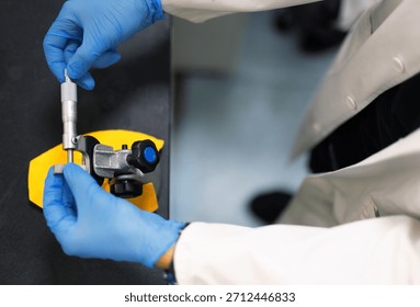 Laboratory technician using a precision micrometer to measure a metal component. Close-up of hands in blue gloves performing accurate dimensional inspection in a research or engineering lab. - Powered by Shutterstock - Get 15% off with code: PIKWIZARD15