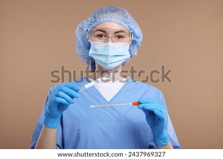Laboratory testing. Doctor with cotton swab and tube on light brown background