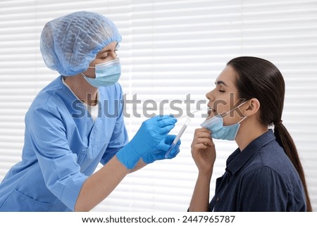 Laboratory testing. Doctor taking sample from patient's mouth with cotton swab in hospital