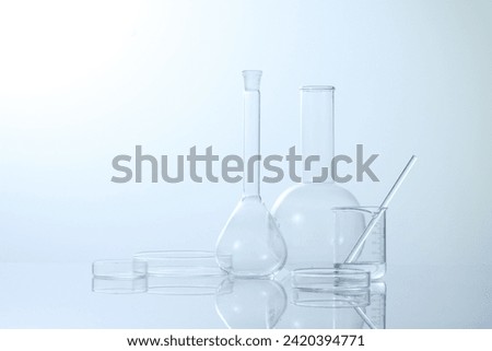 Laboratory utensils Beaker flask measuring cylinder Glass rod Petri dish against a light blue background. 