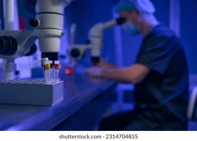 Laboratory worker examining samples under microscope in clinic