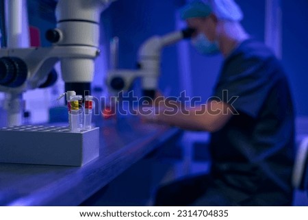 Laboratory worker examining samples under microscope in clinic
