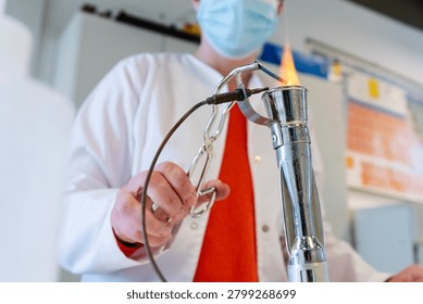 Laboratory Worker Heating Material Over Gas Bunsen Burner Flame in Chemistry Lab