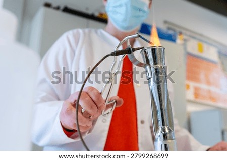Laboratory Worker Heating Material Over Gas Bunsen Burner Flame in Chemistry Lab