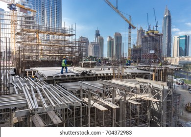 Laborers working on modern constraction site works in Dubai. Fast urban development consept.