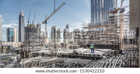 Laborers working on modern constraction site works in Dubai. Fast urban development consept.