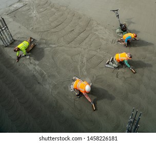 Labors Finishing The Garage Basement Floor After Foundation Concrete Mat Pour. 