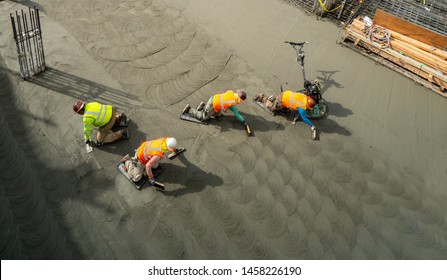 Labors Finishing The Garage Basement Floor After Foundation Concrete Mat Pour. 