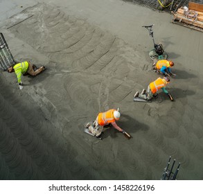 Labors Finishing The Garage Basement Floor After Foundation Concrete Mat Pour. 