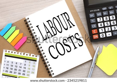 LABOUR COSTS open notebook with stickers and a calendar for the month. word on the page