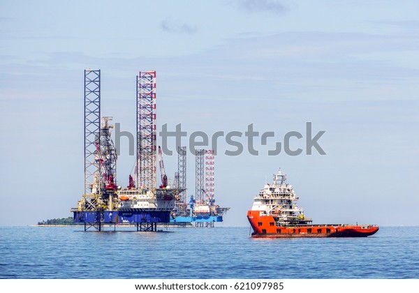 Labuan,Malaysia-Mac 25,2017:Multi function offshore\
support & platform supply vessel with the lay up drilling\
jackup rigs in Labuan waters in the Brunei Bay area at\
Labuan,Malaysia on 25th March\
2017.