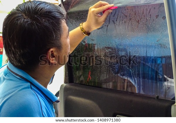 Labuan,Malaysia-May 25,2019:Worker applying\
tinting foil onto car window in Labuan,Malaysia.The new rules for\
vehicle window tints,allowing ‘unlimited’ visible light\
transmission\
percentages.
