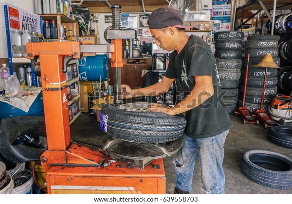 Labuan,Malaysia-May\
9,2017:Car tire service mechanic changing car wheel before makes\
computer wheel balancing on special equipment machine tool in auto\
repair service in\
Labuan,Malaysia.