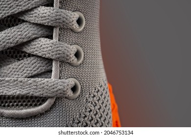 Laced up gray mesh fabric sneakers macro shot. Laced fastening of new orange sole sport shoe close-up. Elastic laces of modern textile trainers for active lifestyle, sport and fitness. Copy space.