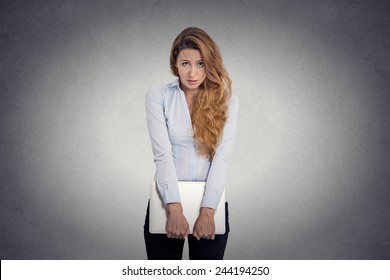 Lack Of Confidence. Insecure Worried Young Woman Holding Laptop Feels Awkward Isolated Grey Wall Background. Human Face Expression Emotion Body Language Life Perception  