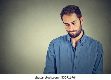 Lack Of Confidence. Shy Young Handsome Man Feels Awkward Isolated On Grey Wall Background. Human Emotion Body Language Life Perception