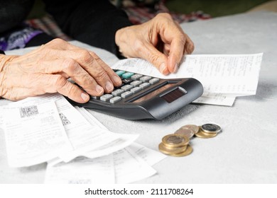 Lack of money in old age. Elderly woman wrinkled hands count receipts with calculator. Poverty in old age, small pension concept.