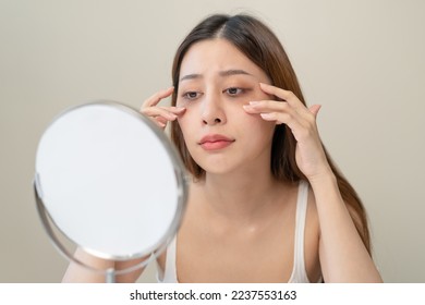 lack of sleep problem, Worried Asian young woman pointing finger at dark circles under her eyes - Shutterstock ID 2237553163