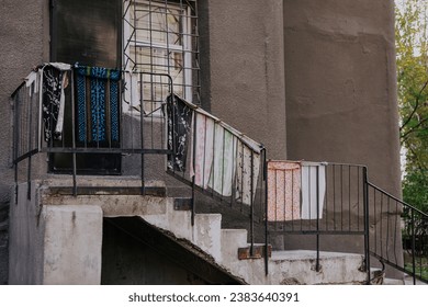 Lack of space in living quarters. Towels drying outside, hanging on the staircase railing, near the door, entrance to the room. Courtyard of a residential building in the CIS countries.
