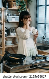 Lackless Sleep Chinese Lady Rubbing Eyes And Holding The Cup Of Hot Milk In The Kitchen. Weekend Relaxation Time.