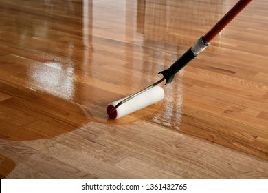 Lacquering wood floors. Worker uses a roller to coating floors. Varnishing lacquering parquet floor by paint roller - second layer. Home renovation parquet - Shutterstock ID 1361432765