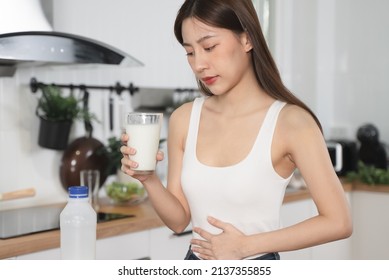 lactose intolerance concept. Woman holding a glass of milk and having a stomachache.