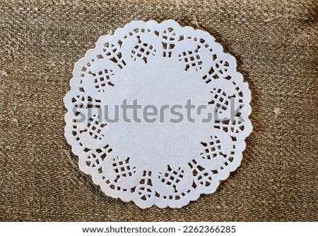 Lacy white paper napkin on rustic background. Concept circular elements or framing.