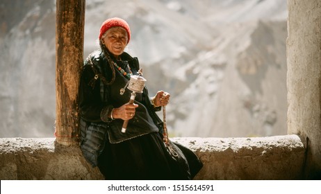 LADAKH, INDIA- OCT 6, 2018: an old tibatan lady practicing meditation using brass prayer wheel at Lamayuru monastry.