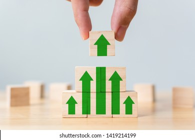 Ladder career path for business growth success process concept. Wood block stacking as step stair with arrow up. Hand putting wooden cube block on top pyramid