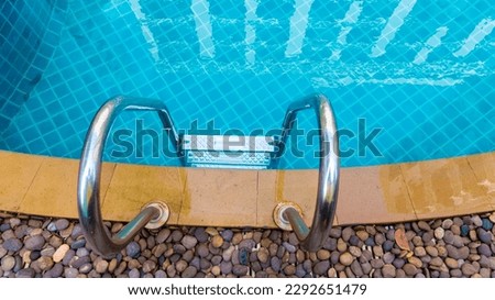 Ladder stainless handrails for descent into swimming pool. Swimming pool with handrail . Ladder of a swimming pool. Horizontal shot. stairs swimming pool. Stainless steel ladder