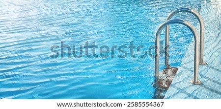 Ladder stainless handrails (stairs) into the swimming pool with blue beautiful water and sunlight (blik of sun). Vacation, resort, healthy lifestyle, sport concept.