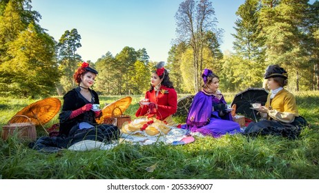 Ladies in 19th century dresses at a picnic hold cups of drinks and chat