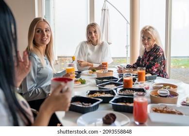 Ladies chatting, laughing and eating dinner in office. Friendly work team enjoying positive emotions and lunch together. Happy colleagues staff group having fun during the break. - Powered by Shutterstock