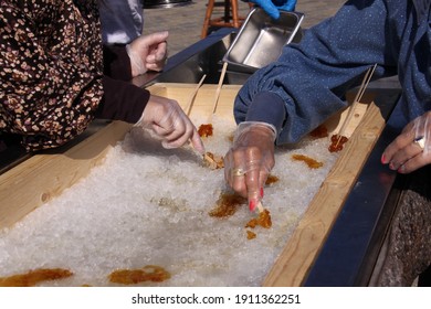 Ladies' Hands Making Maple Syrup Snow Candy