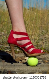 Ladies Leg - Foot In The Court Shoe And A Tennis Ball.A Woman In A Pump Shoe Standing On A Yellow Tennis Ball. Woman Standing On Overgrown Train Track.