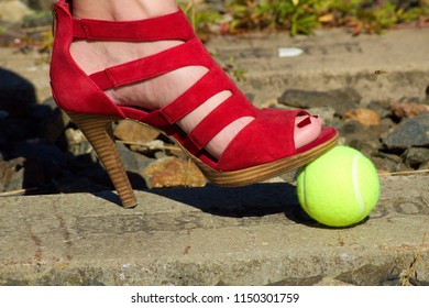 Ladies Leg - Foot In The Court Shoe And A Tennis Ball.A Woman In A Pump Shoe Standing On A Yellow Tennis Ball. Woman Standing On Overgrown Train Track.