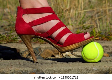 Ladies Leg - Foot In The Court Shoe And A Tennis Ball.A Woman In A Pump Shoe Standing On A Yellow Tennis Ball. Woman Standing On Overgrown Train Track.