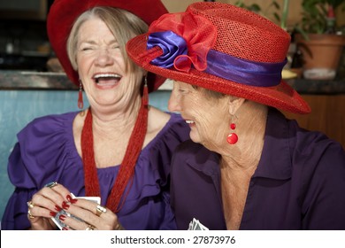 Ladies wearing red hats playing a hand of cards - Powered by Shutterstock