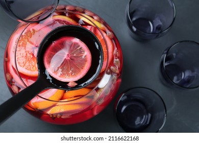 Ladle With Aromatic Punch Drink Above Glass Bowl On Black Table, Top View