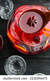 Ladle Of Delicious Aromatic Punch Drink Over Bowl On Black Wooden Table, Flat Lay