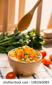 Ladle Of Steamed Freshly Harvested Young Vegetables Including Crinkle Cut Sliced Carrots, Peas And Potato For A Healthy Accompaniment To Dinner