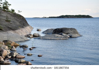 Ladoga Northen Lake With Island On Backside And Stone Shore. Sky Without Clouds. Still Water. Water Level On The Rock. Summer.