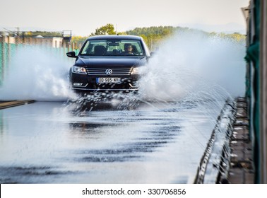 LADOUX, FRANCE - SEPTEMBER 16, 2014: Tire test is held at the proving ground. Test-driver performs a longitudinal aquaplanning test to determine the tire which provides the best grip with wet road.