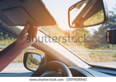Lady adjust sun visor while driving car on highway road - interior car using concept