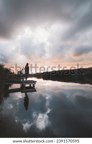 Similar – Image, Stock Photo Lady aged 20-25 standing on a wooden pier by a pond watching the sunset over the town of Oostende, western Belgium. Dramatic red-orange sky