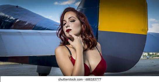 Lady Beautiful Redhead Girl Dressed In Style Pinup Of The Second World War, Next To A Military Plane